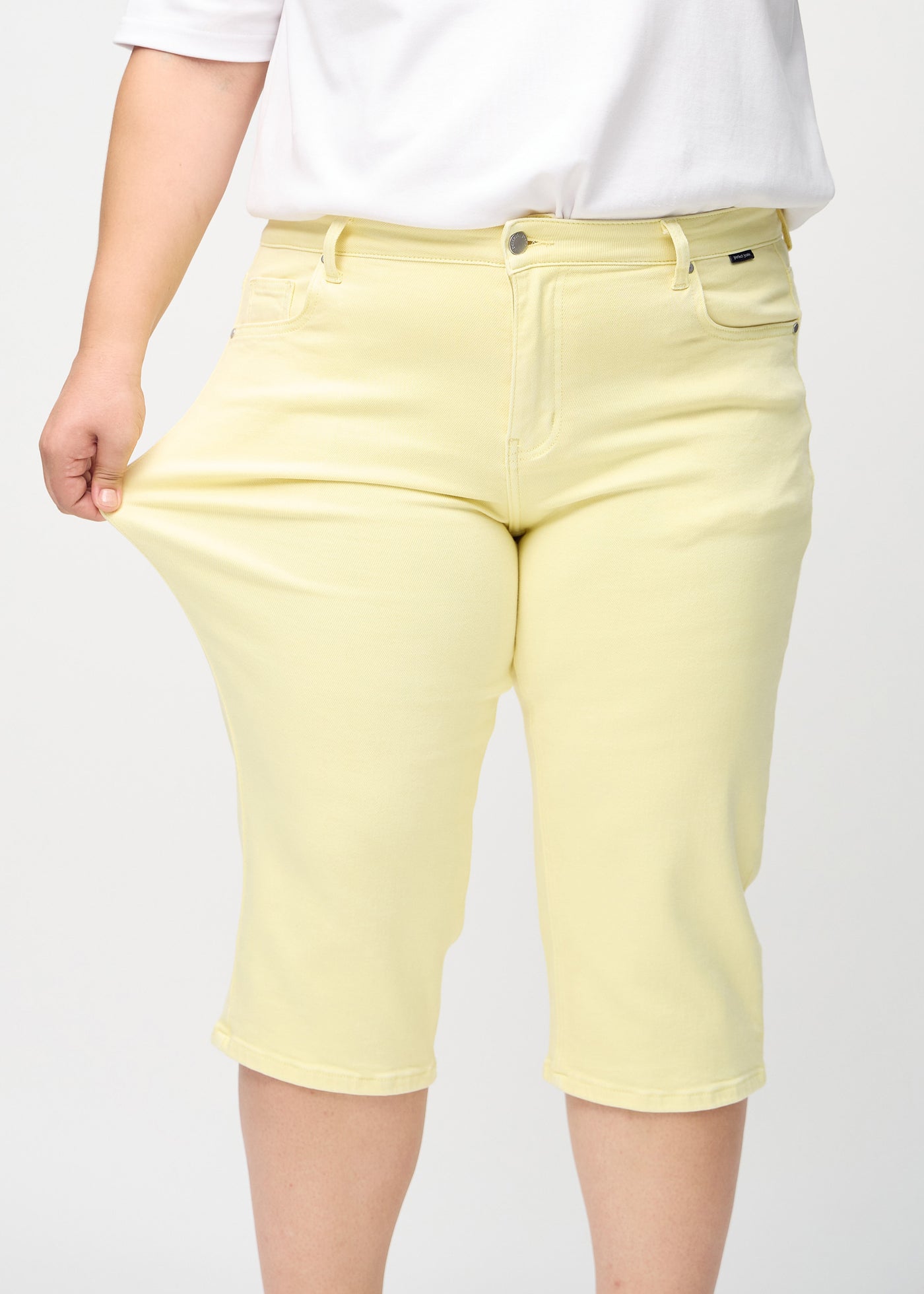 Plus-size model strækker caprisene ved låret for at vise stretch.