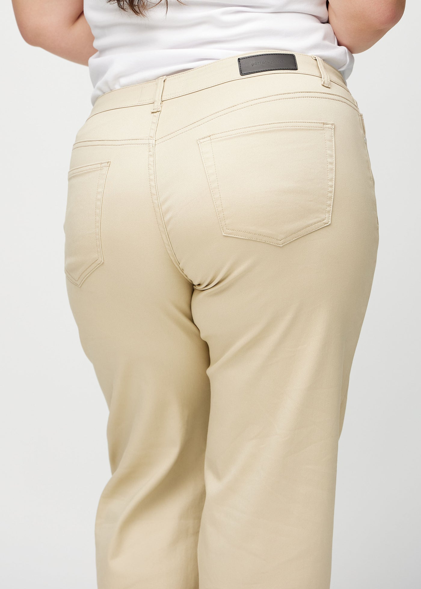 Beige loose jeans set bagfra tæt på en plus-size model for at vise detaljer.