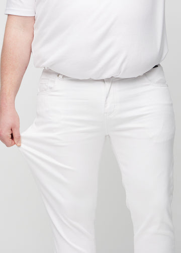 Plus-size model strækker jeansene ved låret for at vise stretch.