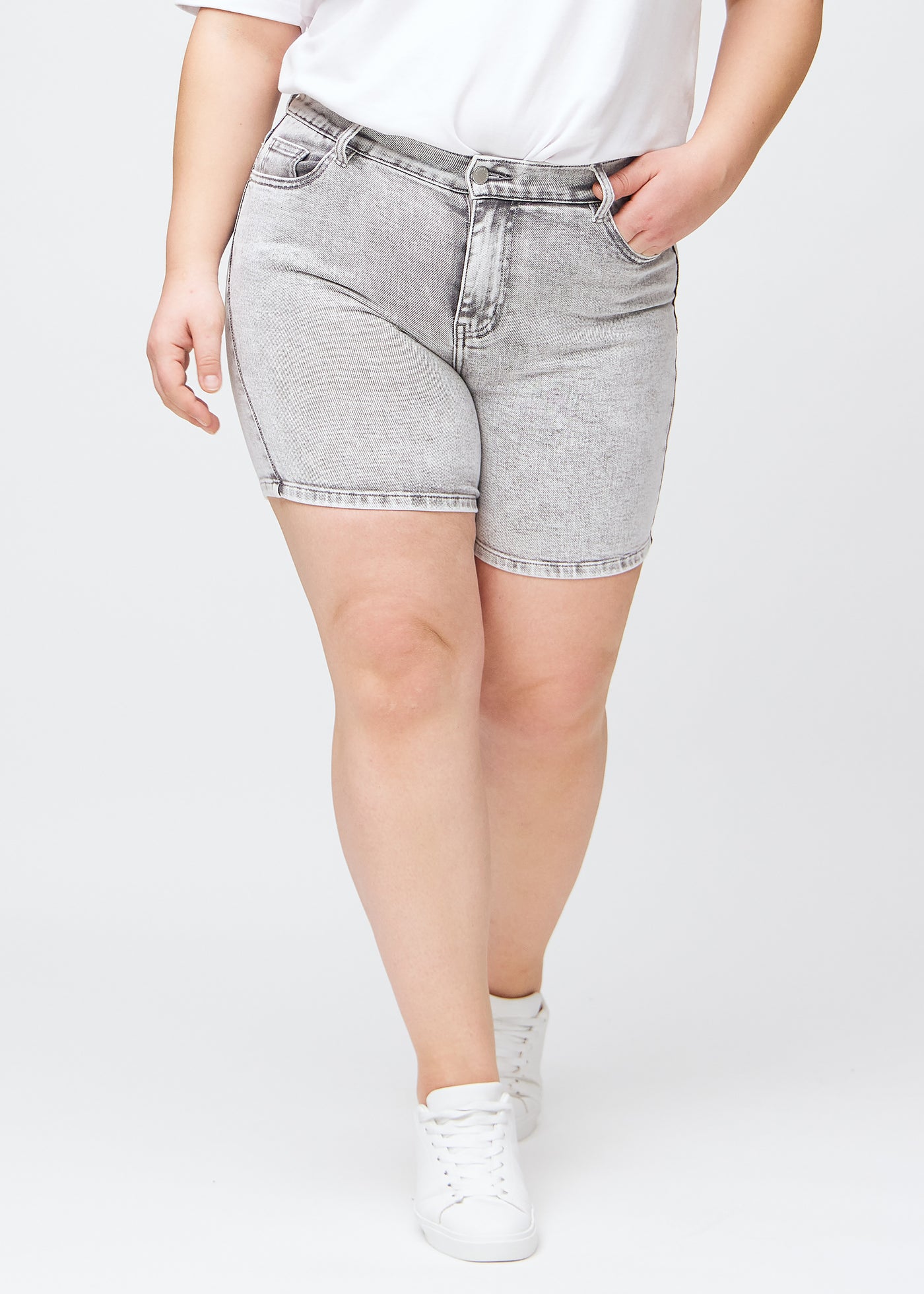 Lysegrå denim skinny short shorts, modelnavn Ashes, som sidder tæt til, og slutter midt på låret på en plus-size model, set forfra.