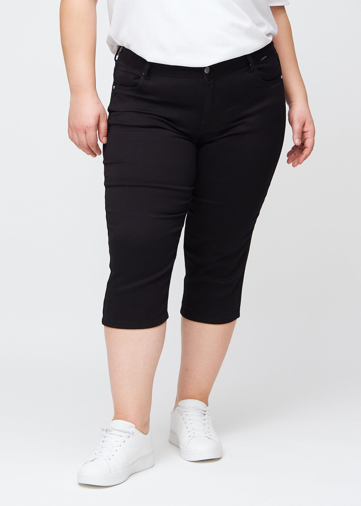 Sorte slim capris, farve Ravens, med tætsiddende pasform og længde lige under knæet – set forfra på plus-size model.