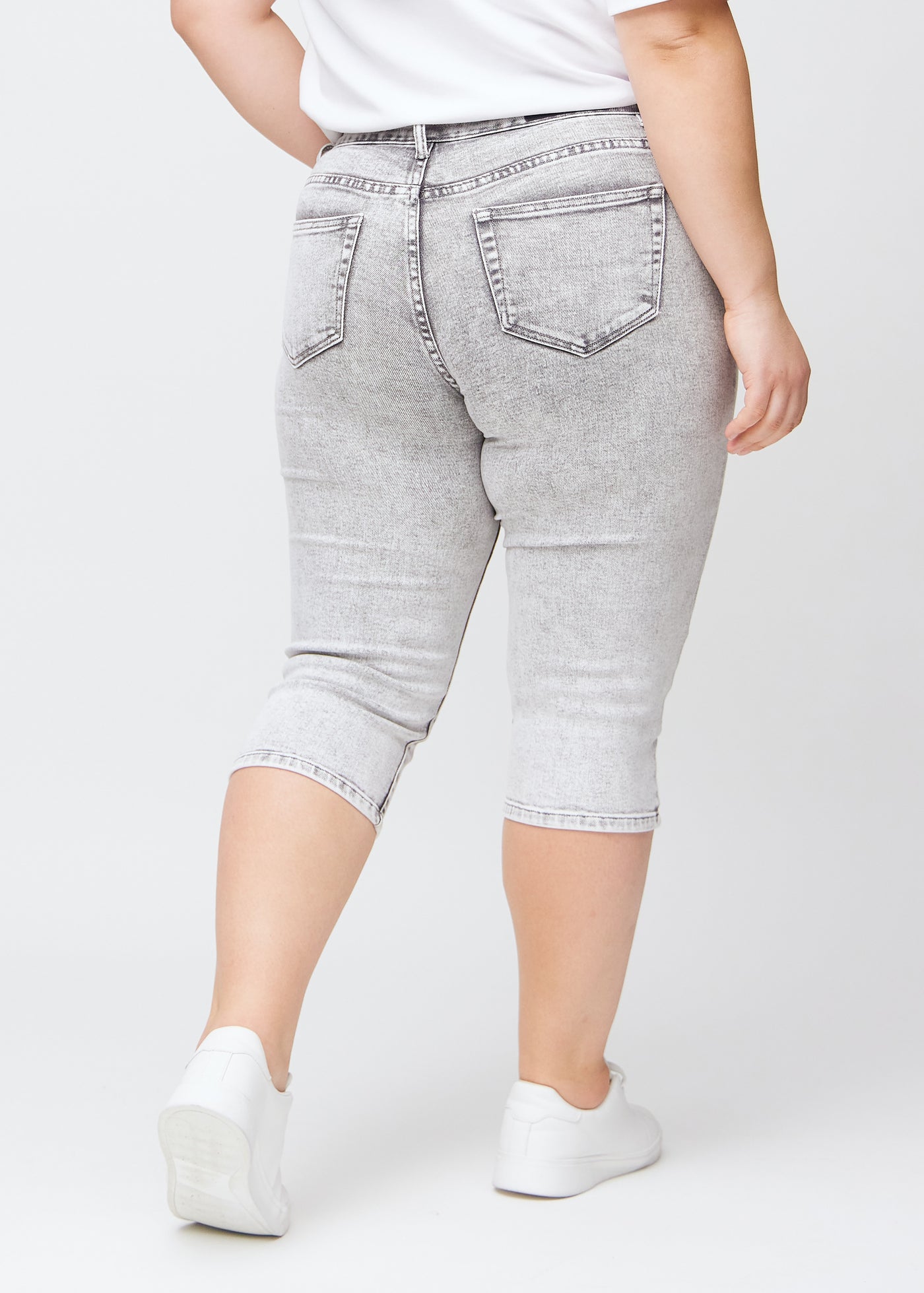 Lysegrå denim slim capris set bagfra på en plus-size model – tydeligt billede af hele produktet og lommer.