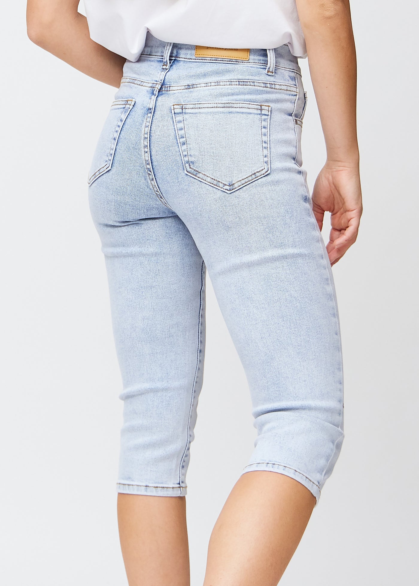 Tæt billede af de lyseblå denim slim capris bagfra, så man tydeligt kan se detaljer og lommer.
