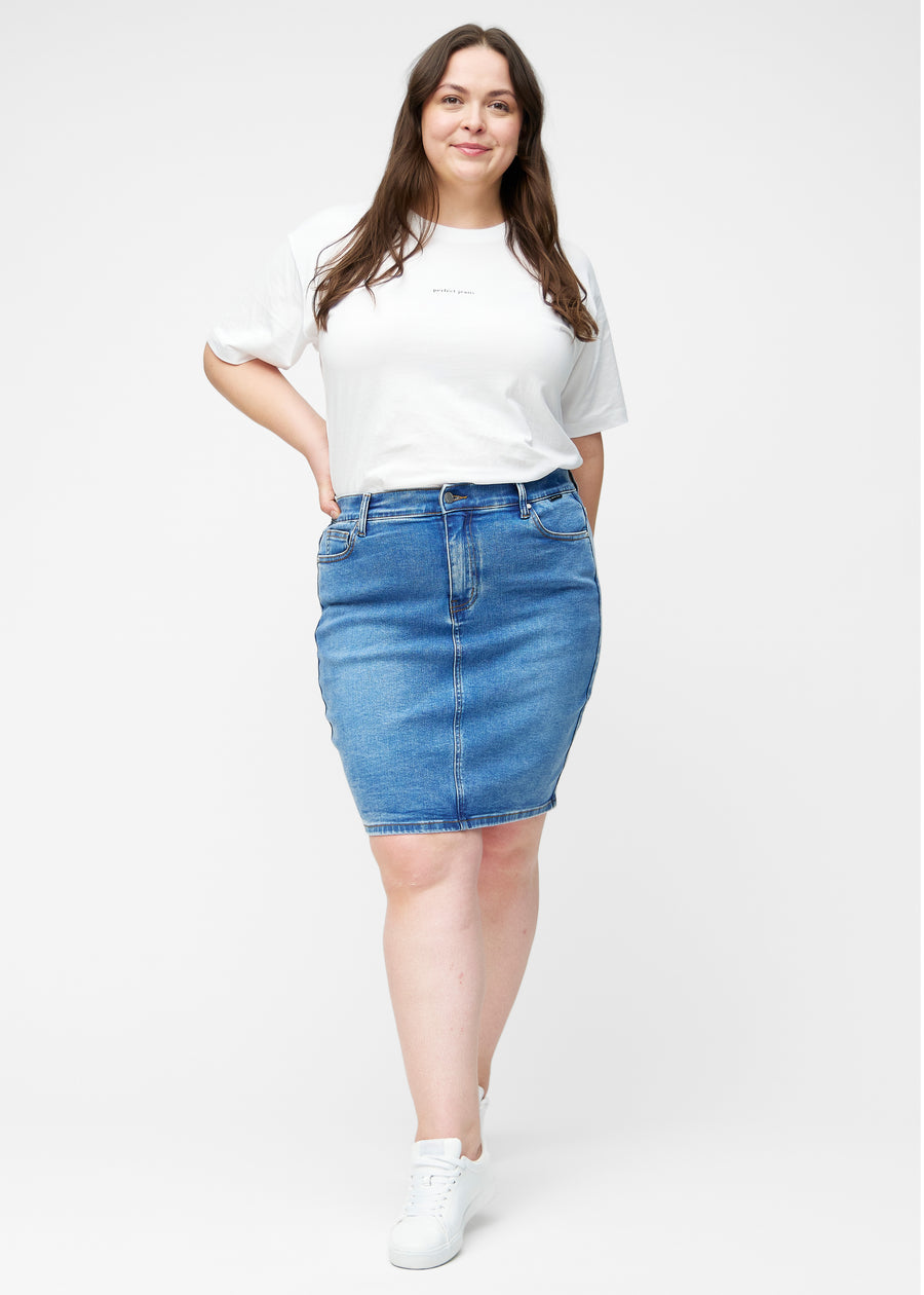 Fuldt billede af plus-size model i klassisk blå, tætsiddende og knælang denimnederdel.