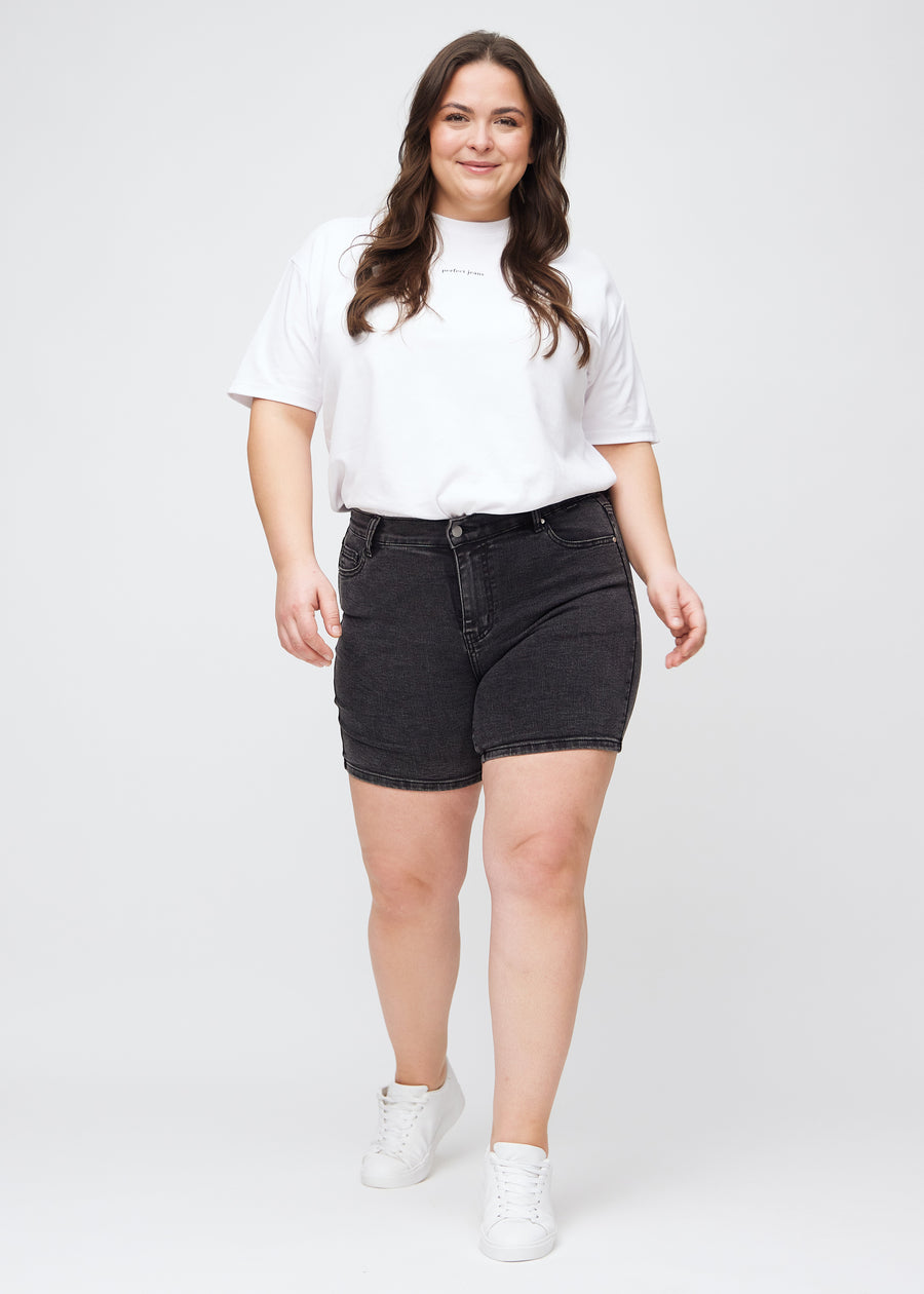 Fuldt billede af en plus-size model i mørkegrå denim skinny short shorts.