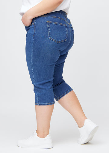Mørkeblå denim slim capris i farven Oceans – set fra siden på en plus-size model, så man ser pasform og silhuet.