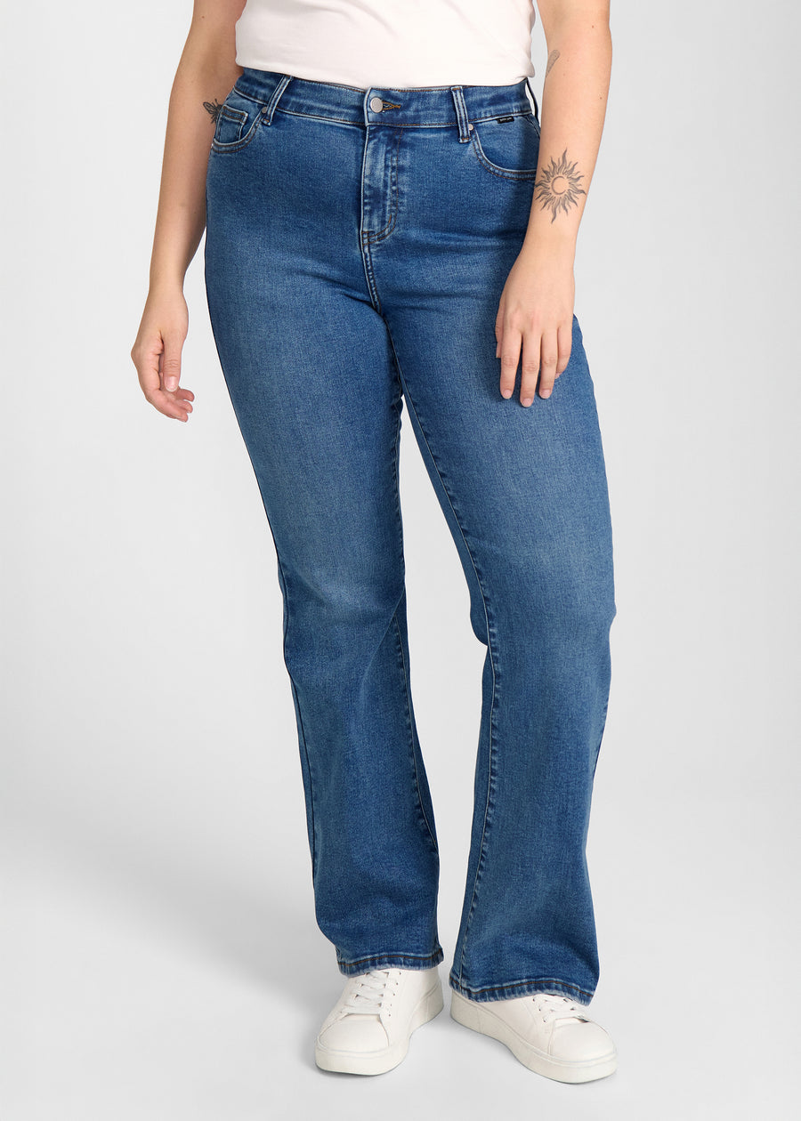 Mørkeblå denim bootcut jeans, modelnavn Oceans, som sidder tæt om hofter og lår med et let svaj fra knæet og ned, set forfra på en plus-size model.