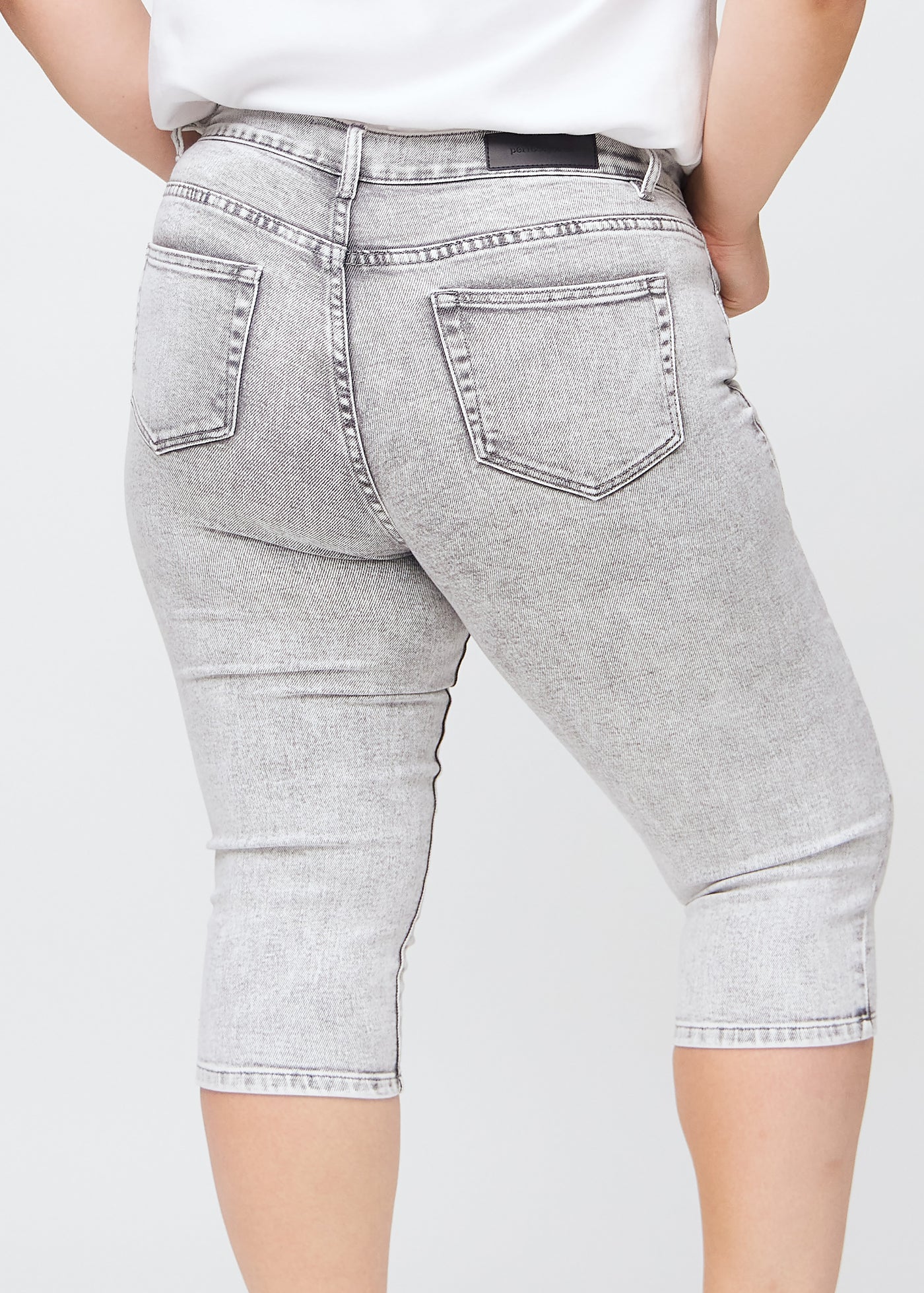 Lysegrå denim skinny capris set bagfra tæt på en plus-size model for at vise detaljer.