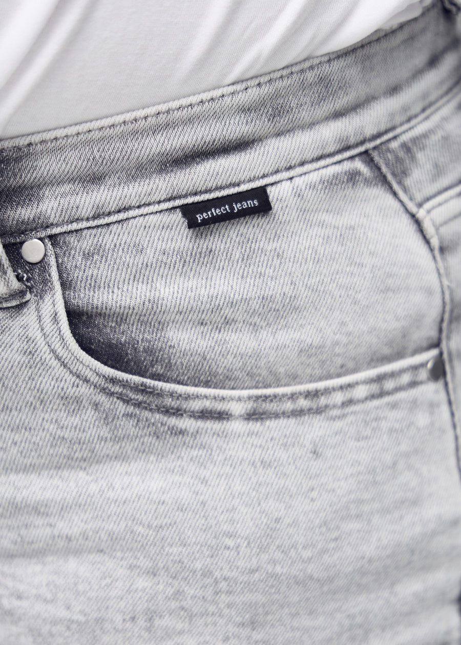 Nærbillede af lysegrå denim med Perfect Jeans logoetiket ved forlommekanten, på en plus-size model.