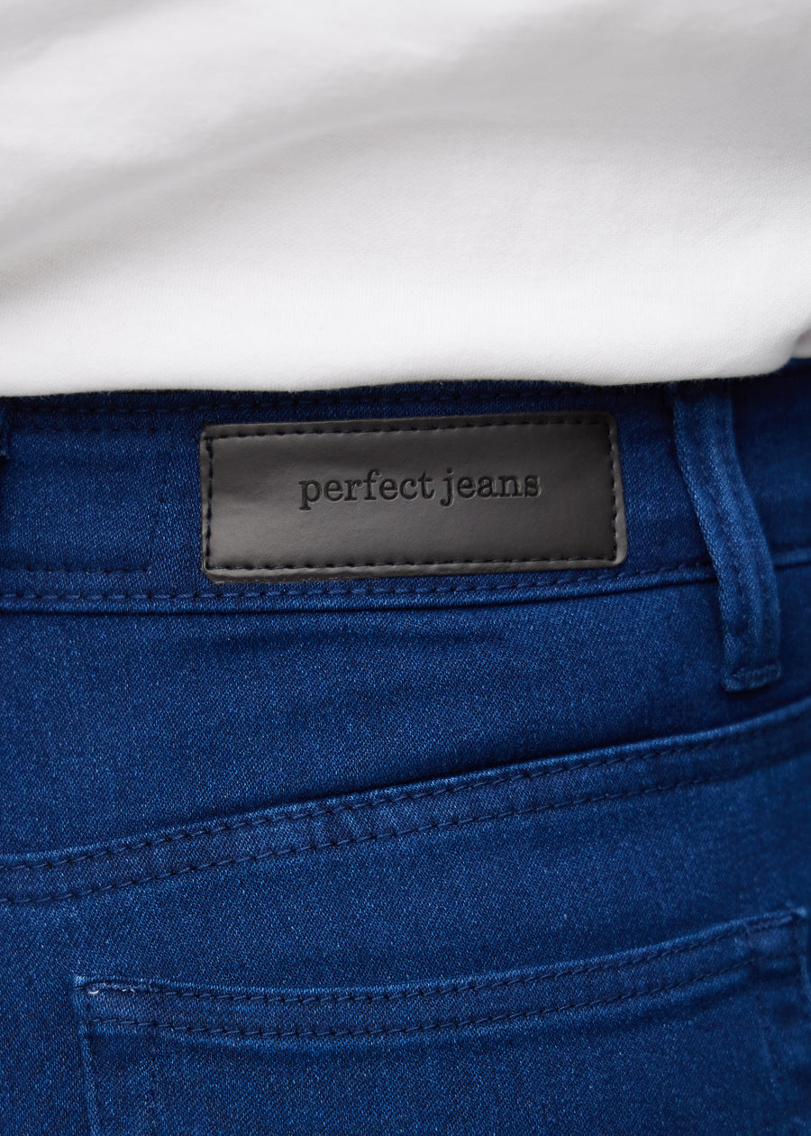 Nærbillede af mørkeblåt jeansmateriale med Perfect Jeans læderpatch bagpå i taljen.