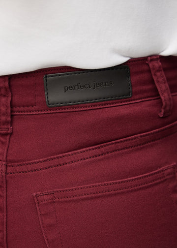 Nærbillede af rødt jeansmateriale med Perfect Jeans læderpatch bagpå i taljen.