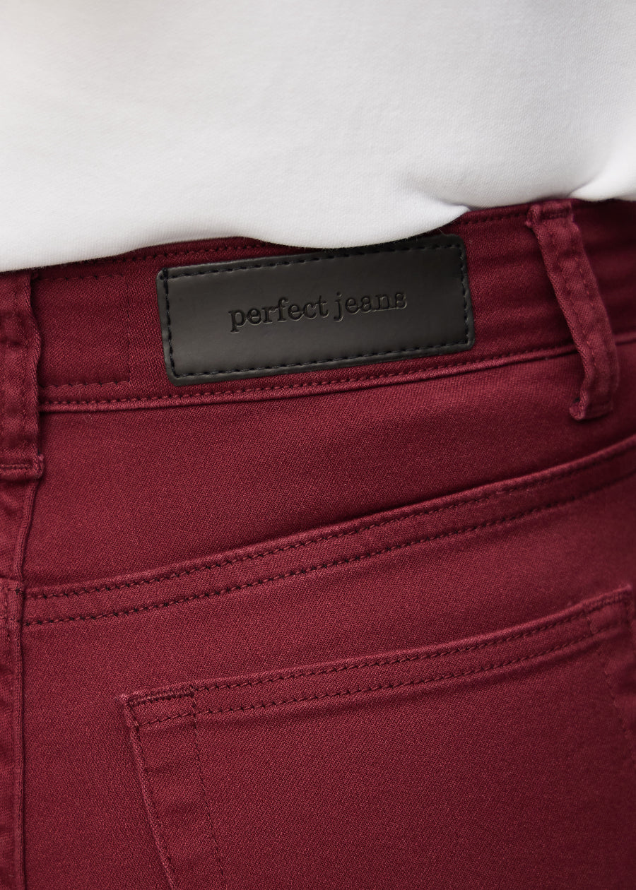 Nærbillede af rødt jeansmateriale med Perfect Jeans læderpatch bagpå i taljen.