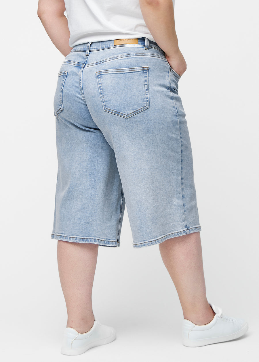 Loose, light blue denim capris in the colour Waves seen from the back on a plus-size model, showing fit and length.
