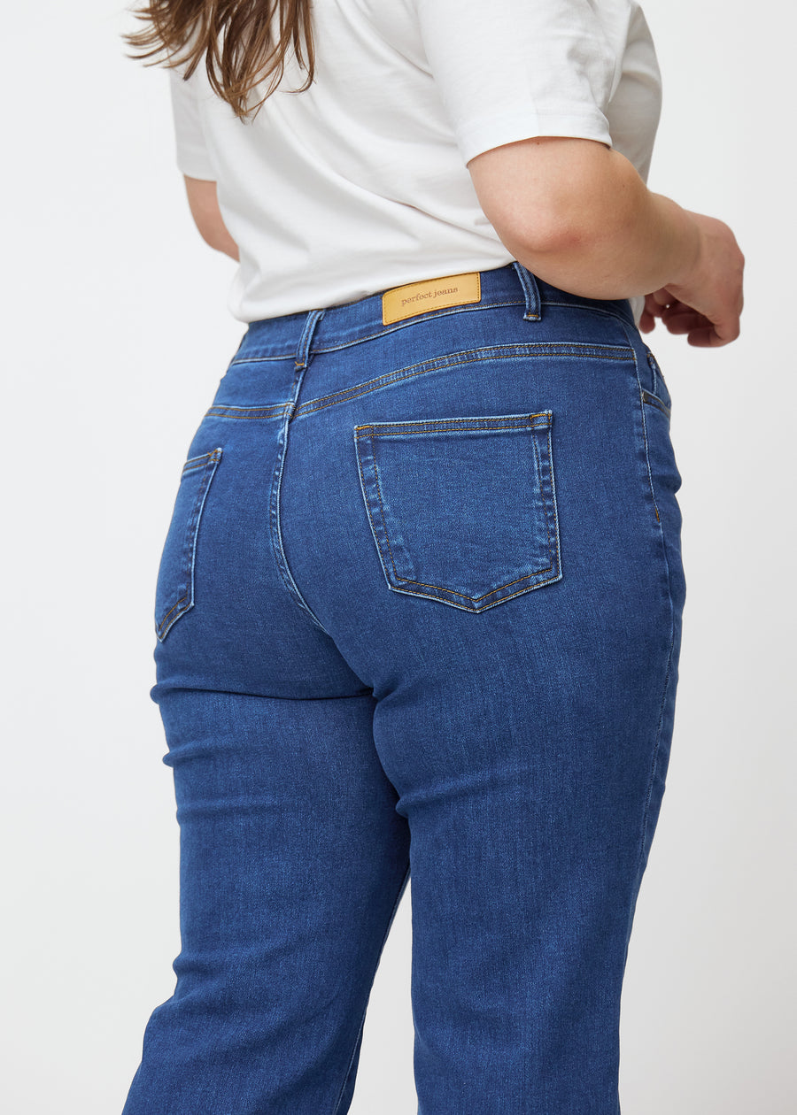 Dark blue mid-rise bootcut jeans in Oceans. Close-up back view on a plus-size model, showing the details.