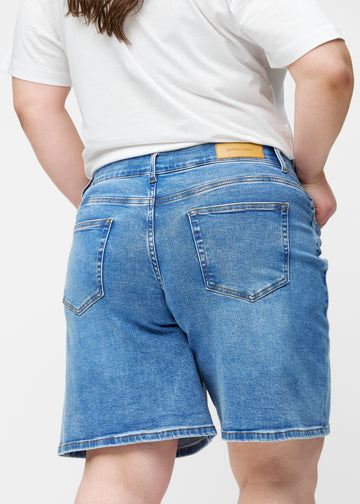 Løse, klassisk blå denim shorts i farven Rivers set bagfra tæt på på plus-size model for at vise pasform og detaljer.