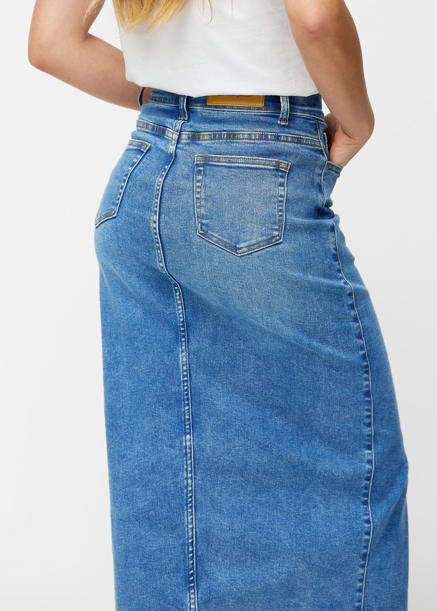 Lang, klassisk blå denimnederdel i farven Rivers set bagfra tæt på for at vise pasform og detaljer.
