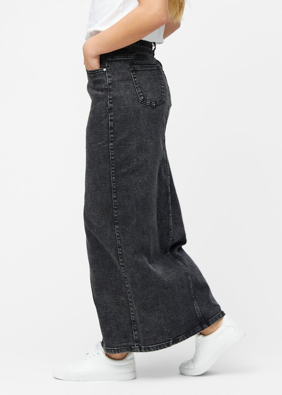 Lang, mørkegrå denimnederdel i farven Shadows med regulær pasform set fra siden på model, med synligt slids foran.