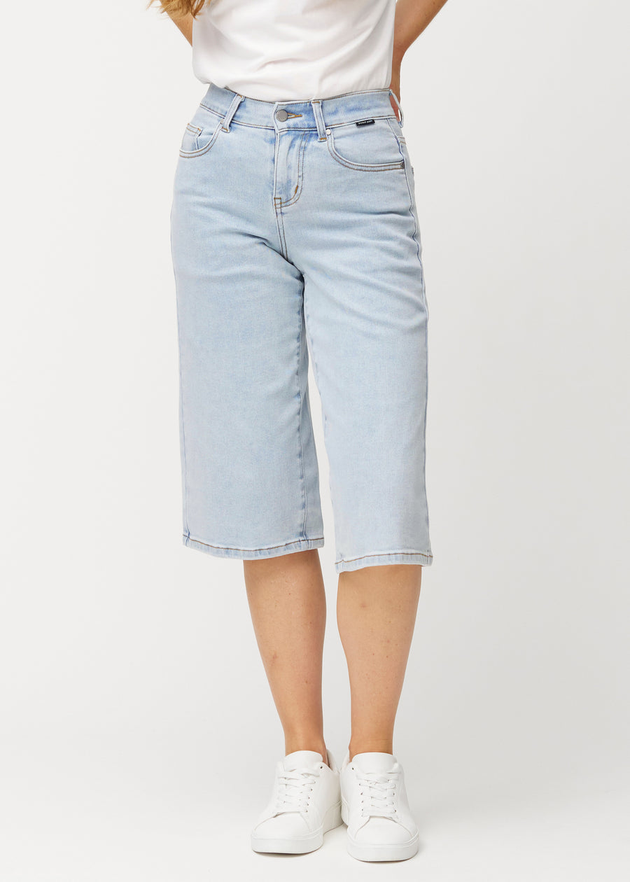 Løse, lyseblå denim capris i farven Waves, der sidder til ved hoften og falder løst ned over lårene til lige under knæet, set forfra.