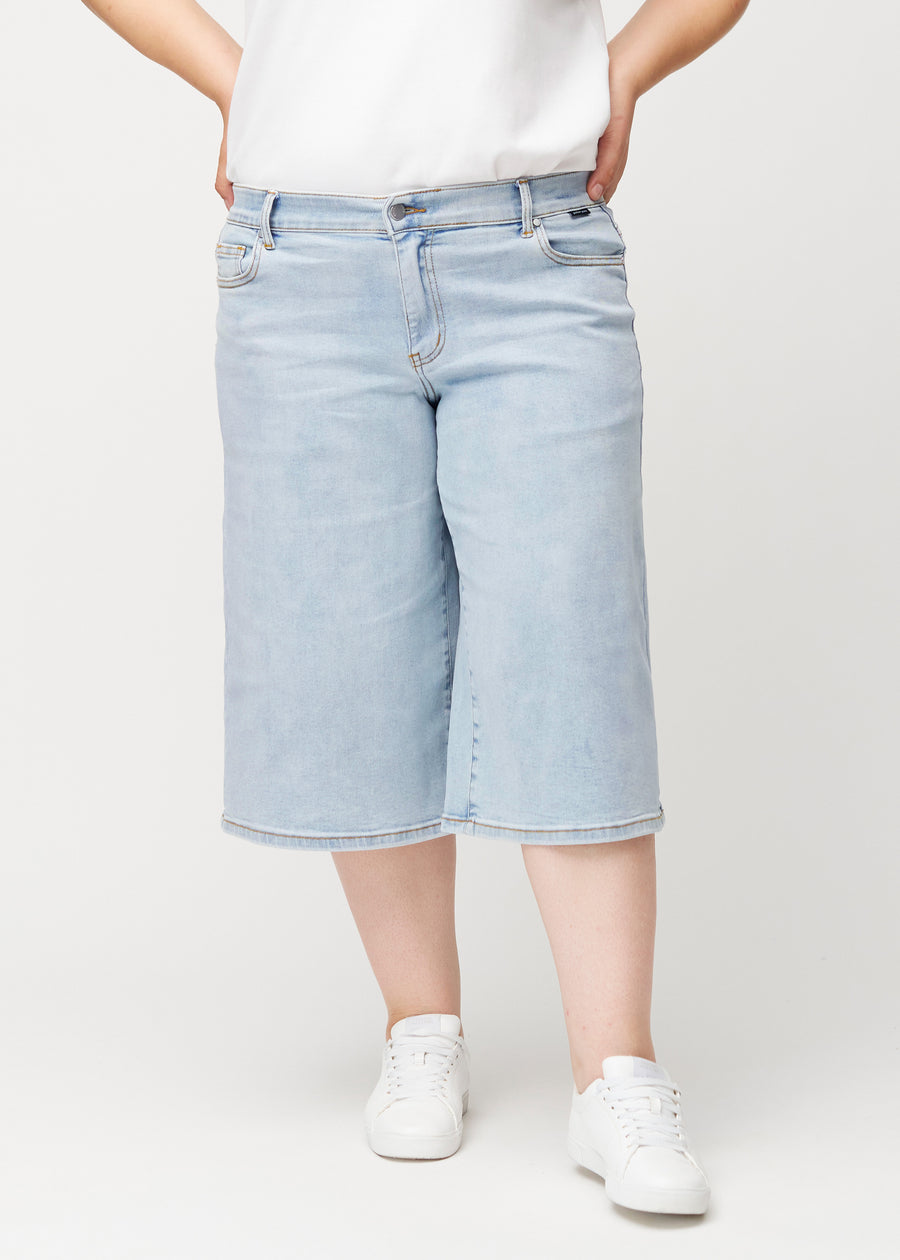 Løse, lyseblå denim capris i farven Waves set forfra på plus-size model, der sidder til ved hoften og falder løst ned.