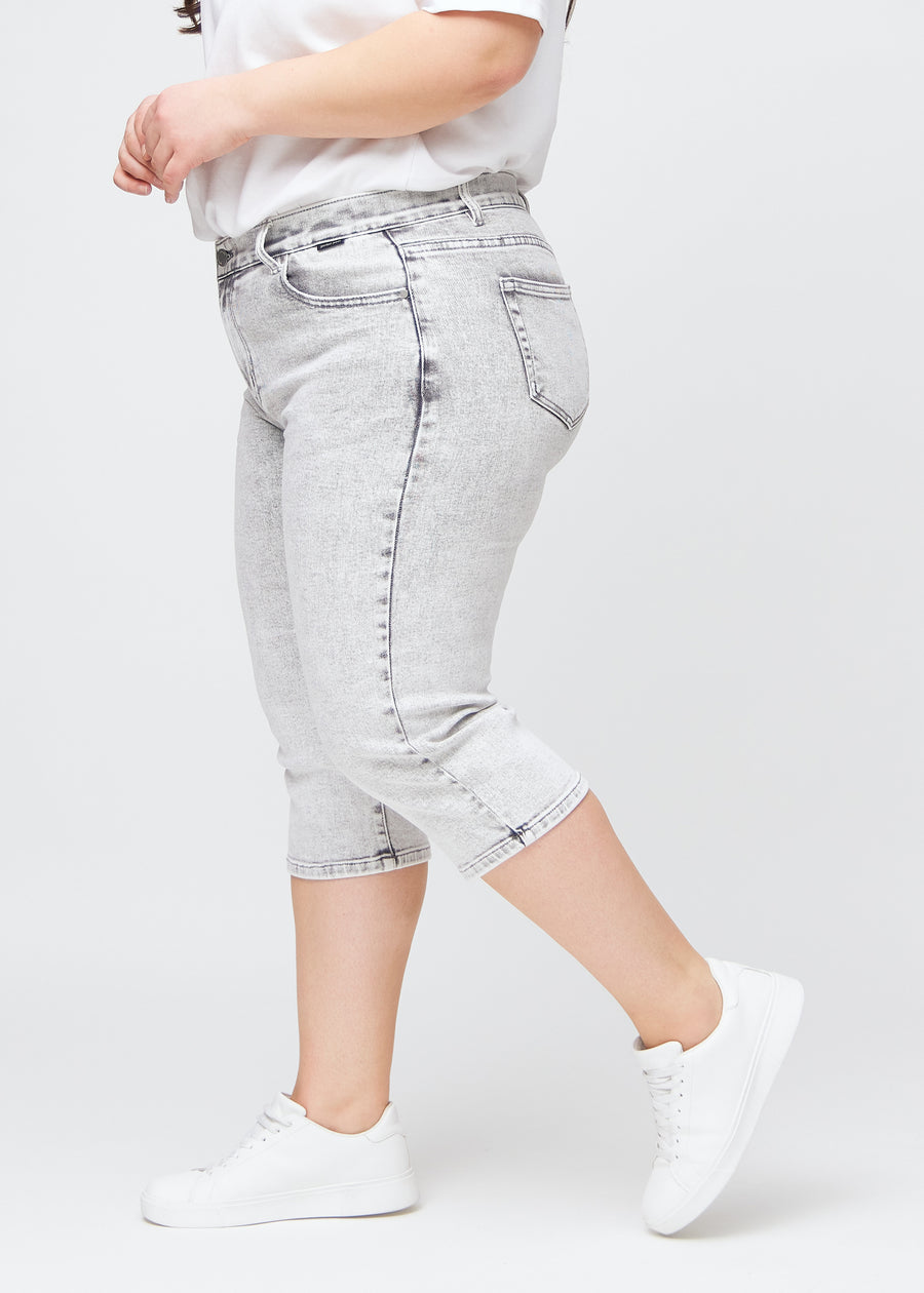 Light grey denim regular capris seen from the side on a plus-size model.