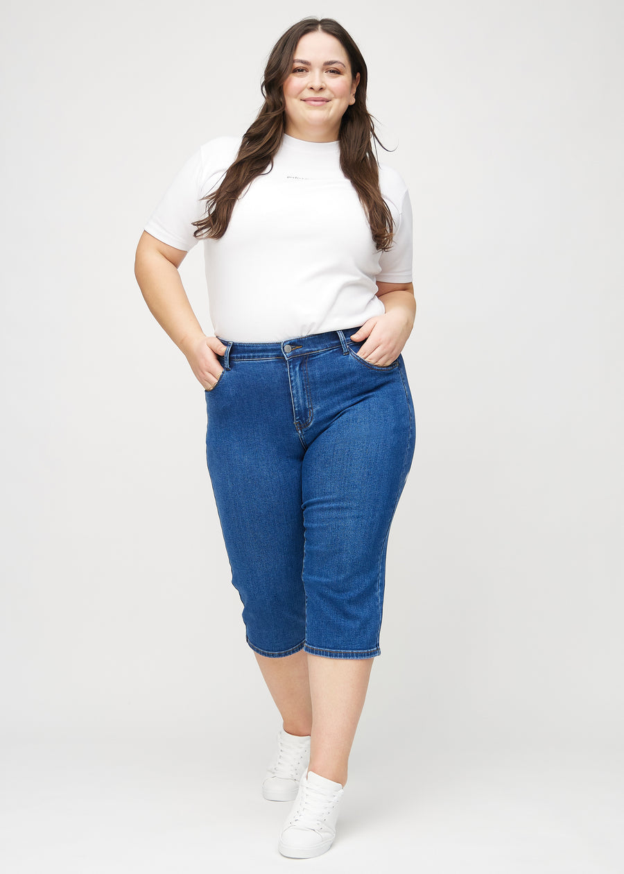 Full image of a plus-size model in dark denim regular capris.