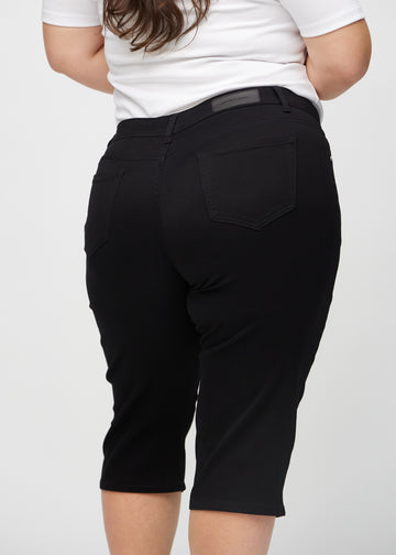 Black regular capris seen from the back close up on a plus-size model to show details.