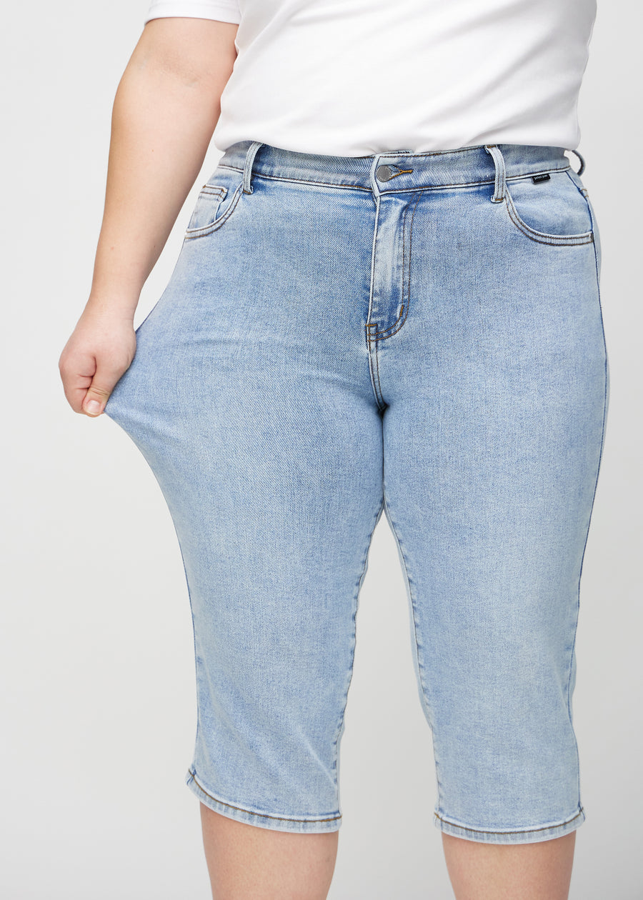 The plus-size model stretches the capris at the thigh to show the stretch.