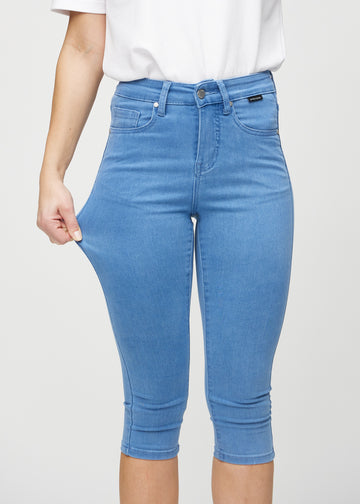 Skinny capris for women in blue fabric, color Geraniums. A model stretches the fabric to demonstrate its flexibility.