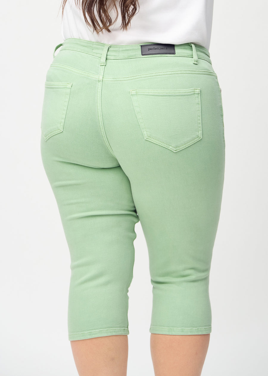 Skinny capris for women in pastel green fabric, color Mints. Close-up from behind on a plus-size model, highlighting pockets and stitching.