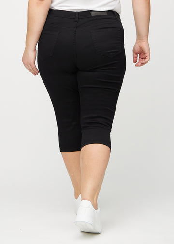 Black skinny capris seen from the back on a plus-size model, so the entire product can be seen.