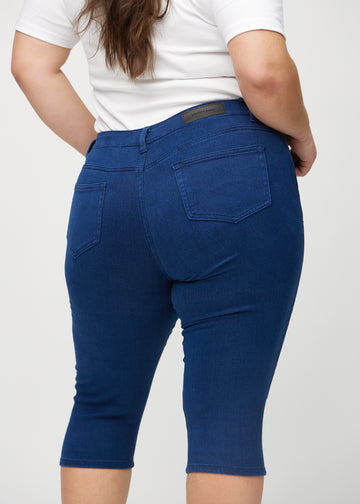 Skinny capris for women in dark blue fabric, color Royals. Close-up from behind on a plus-size model, highlighting pockets and stitching.
