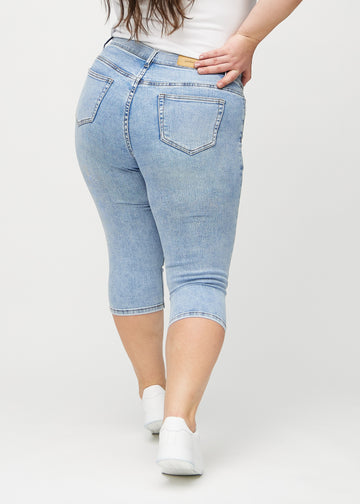 Skinny capris for women in light blue denim, color Waves. Back view on a plus-size model, showing the fit and back pockets.