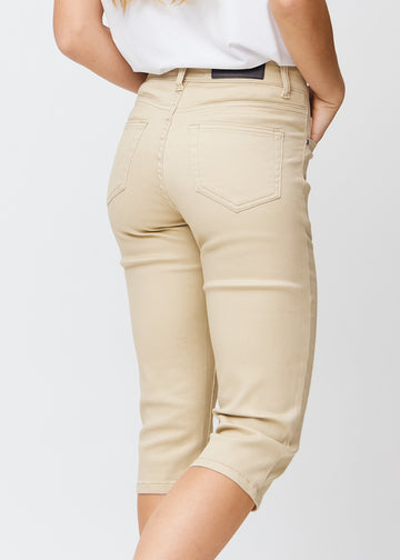 Slim capris for women in beige jeans fabric, color Gazelles. Close-up from behind on a model, highlighting the back pockets and stitching.