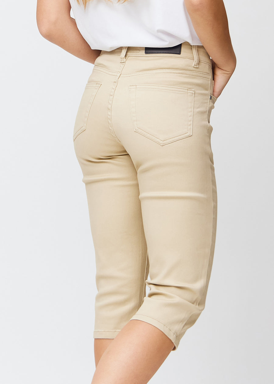 Slim capris for women in beige jeans fabric, color Gazelles. Close-up from behind on a model, highlighting the back pockets and stitching.