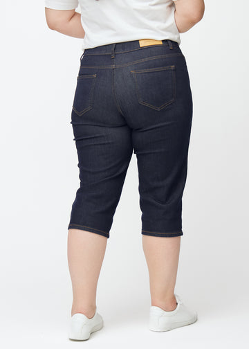 Deep dark blue denim capris for women in the colour Midnights seen from the back on a plus-size model.