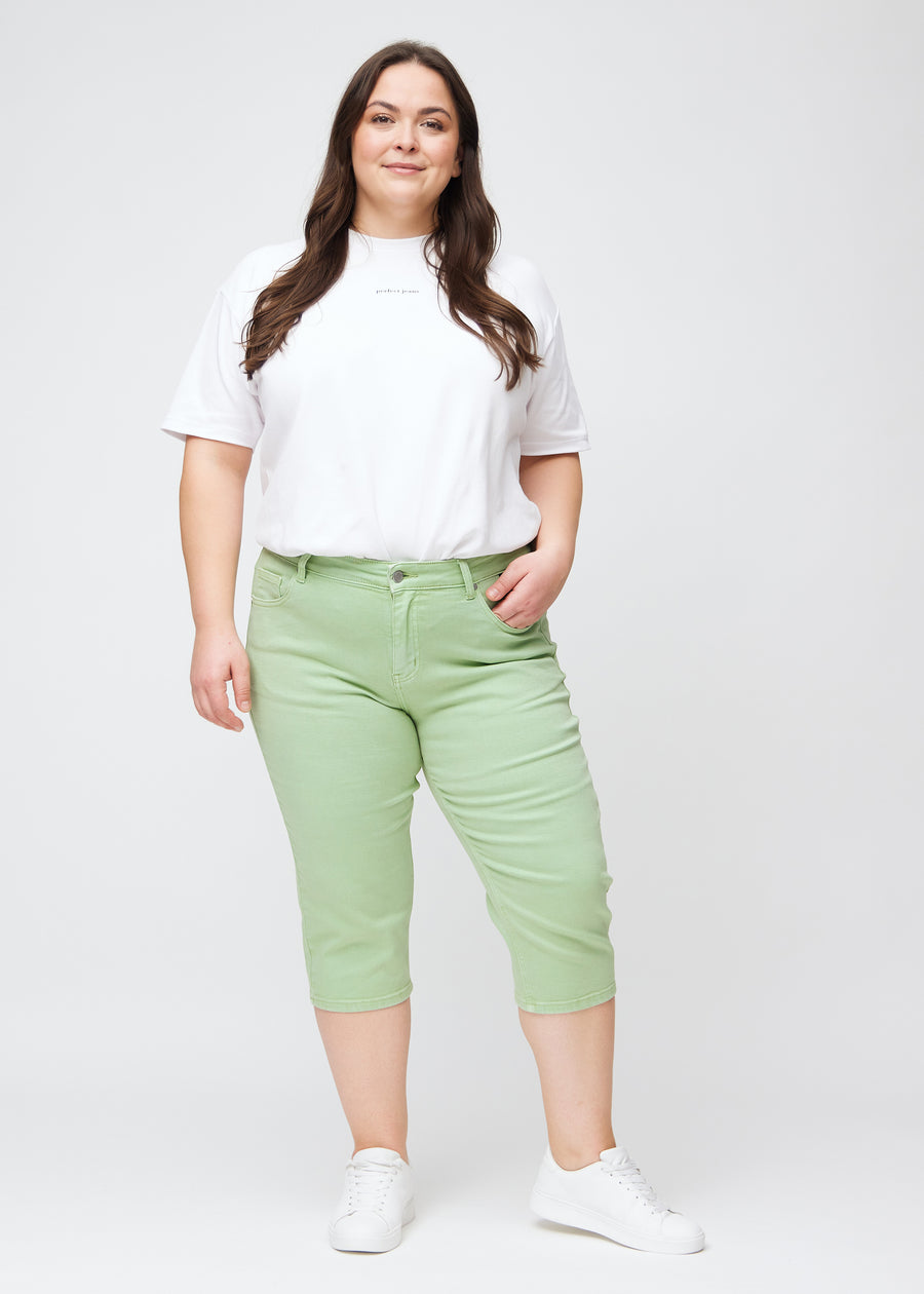 Slim capris for women in pastel light green jeans fabric, color Mints. Full-length view of a plus-size model wearing slim capris.