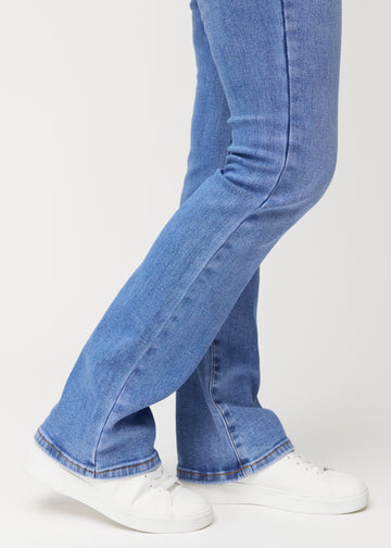 Blue mid-rise bootcut jeans in Rivers. Close-up of the ankle area on a model, showing the subtle bootcut flare.