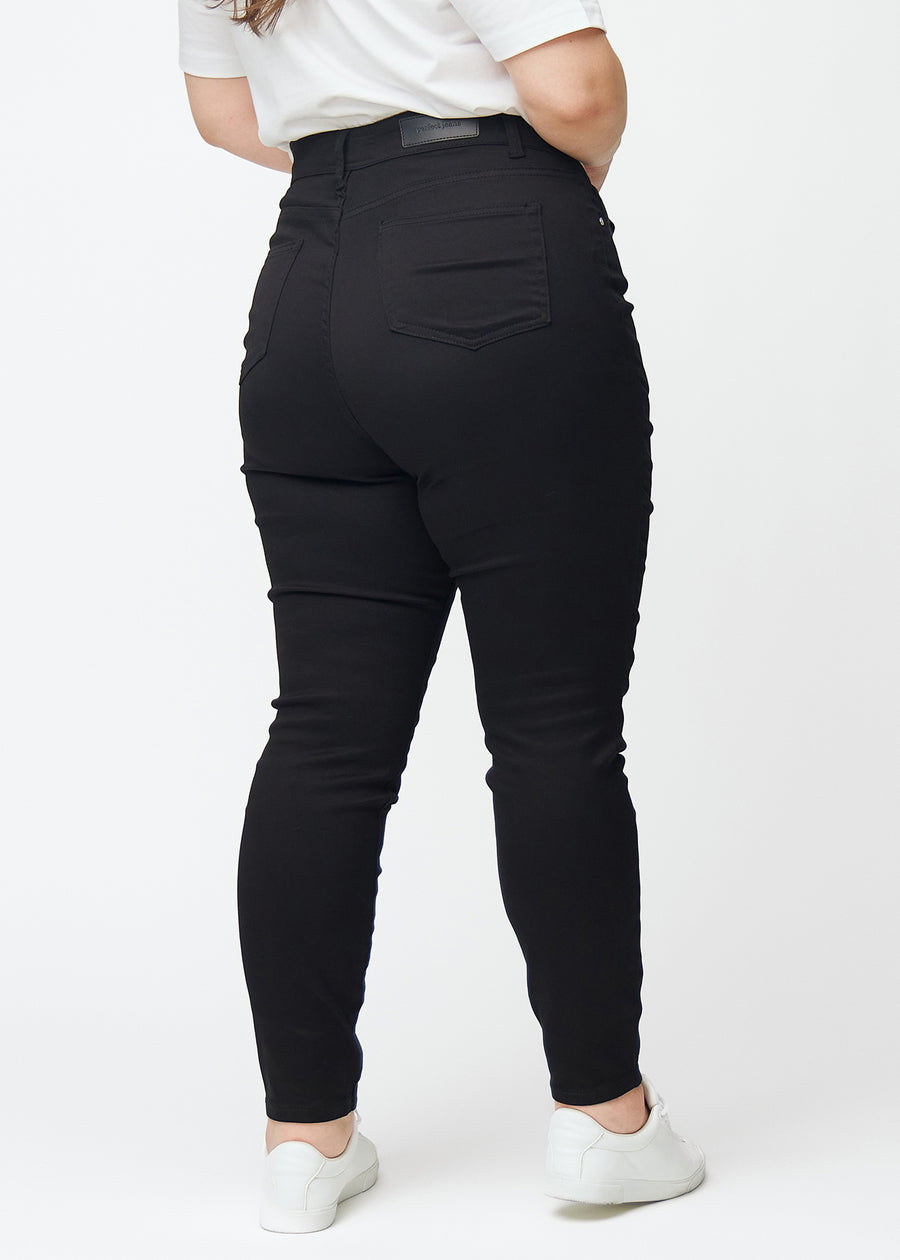 Black plus size jeans with a high waist in the color Ravens with skinny fit are seen from the back on a model.