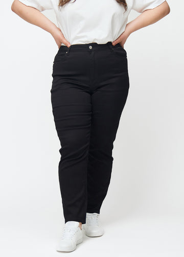 Black high-waisted slim jeans, model name Ravens, which fit closely to the leg, but are slightly looser at the ankle, on a plus-size model, seen from the front.