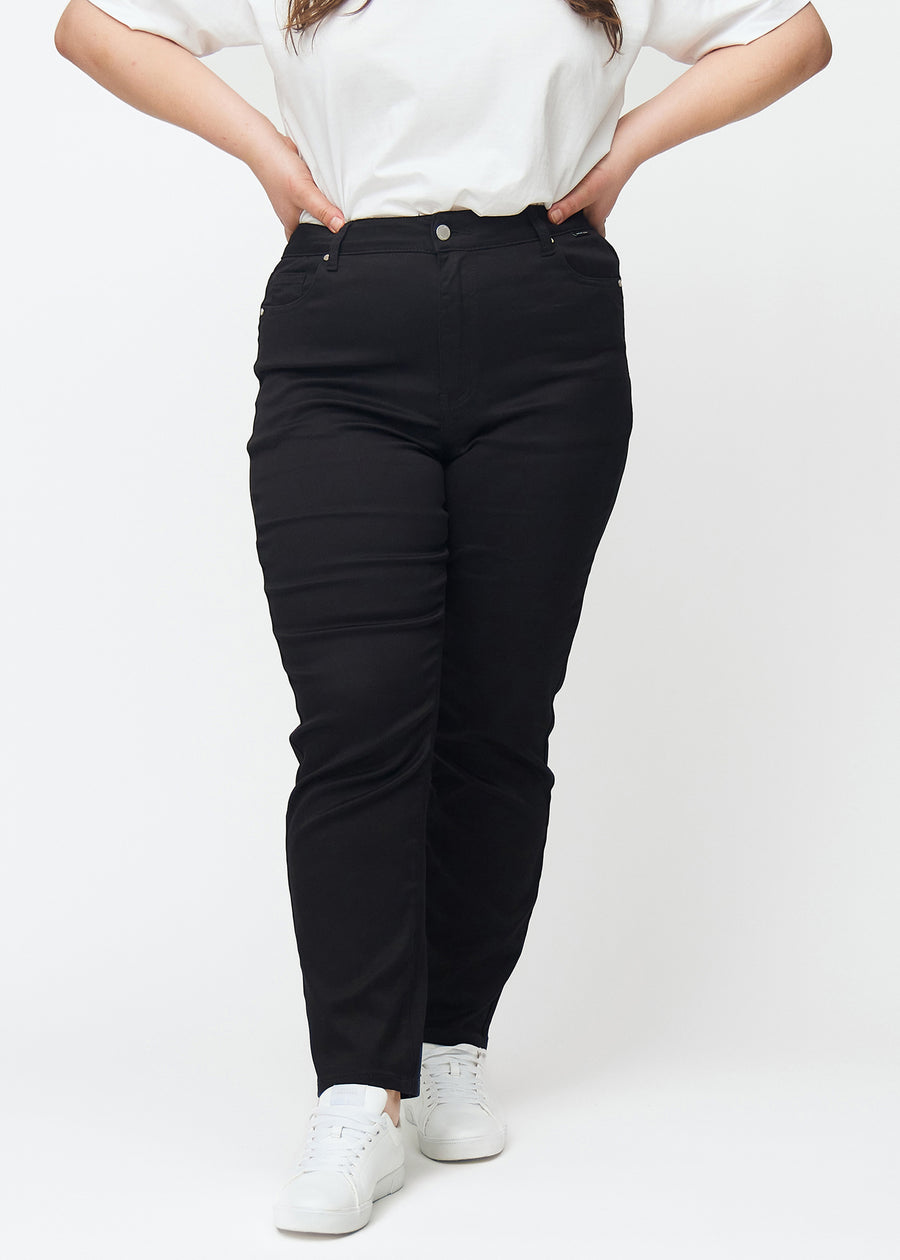 Black high-waisted slim jeans, model name Ravens, which fit closely to the leg, but are slightly looser at the ankle, on a plus-size model, seen from the front.