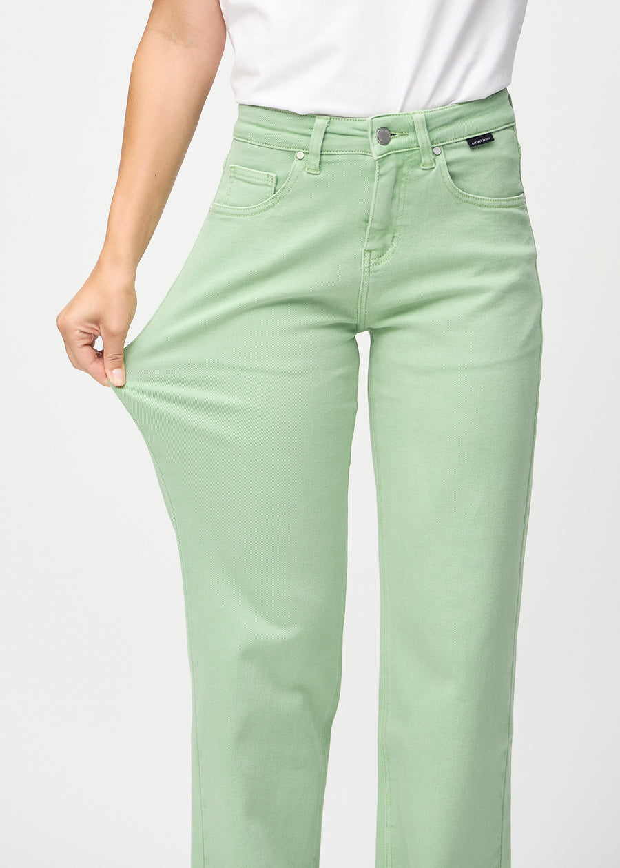 Loose jeans for women in light green, color Mints. A model stretches the denim at the thigh to show the fabric&