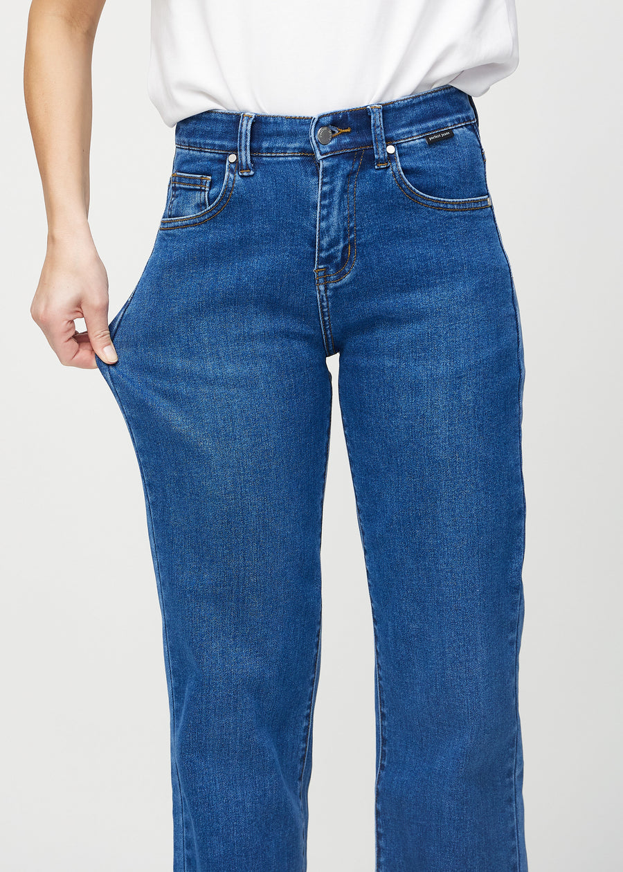 The model stretches the jeans at the thigh to show the stretch.