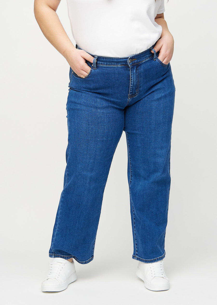 Dark denim loose jeans, model name Oceans, which has a loose fit with plenty of width in the legs on a plus-size model, seen from the front.