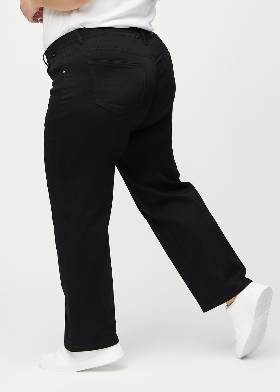 Black loose jeans seen from the side on a plus-size model.