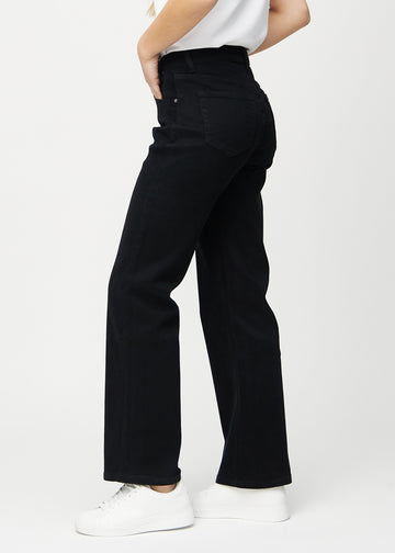 Black loose jeans seen from the side on a model.