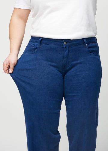 Loose jeans for women in dark blue, color Royals. A plus-size model stretches the denim at the thigh to show the fabric&