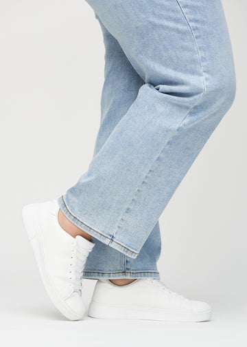 Loose jeans for women in light blue, color Waves. Close-up at the ankles on a plus-size model, showing the wide leg openings.