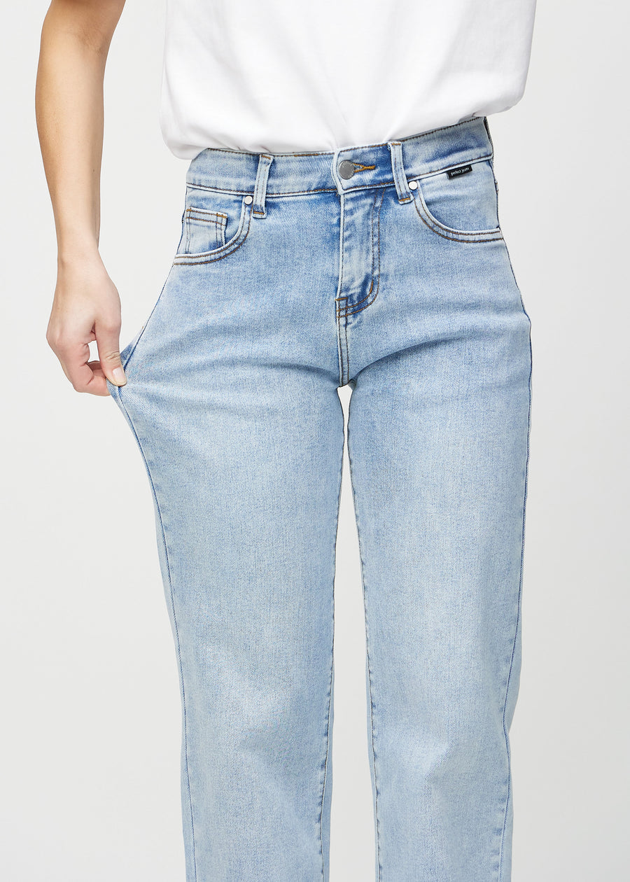 Loose jeans for women in light blue, color Waves. A model stretches the denim at the thigh to show the fabric&
