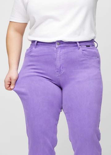 Regular jeans for women in purple, color Lavenders. A plus-size model stretches the fabric at the thigh to show its stretch.