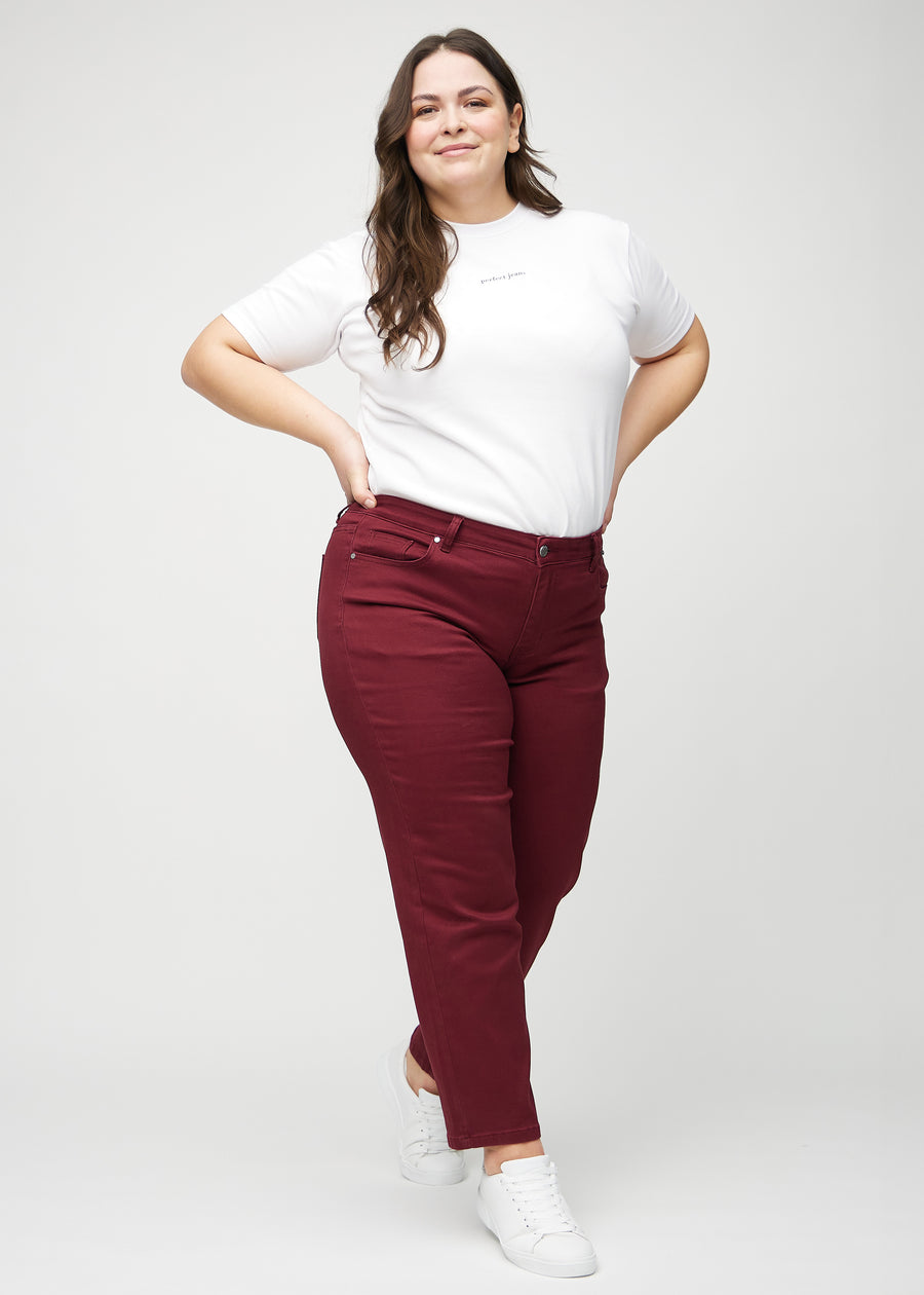 Regular jeans for women in dark red, color Santas. Full-length view of a plus-size model wearing the jeans.
